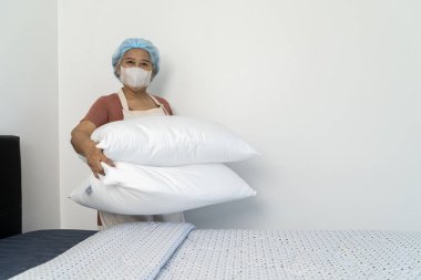 Asyalı temizlikçilerin seçici odak elleri koruyucu eldiven ve önlük takarken oturma odasında sprey şişesi ve cam sileceği tutarken gülümsüyor. Orta yaşlı kadın Cam Temizlemeye Hazır