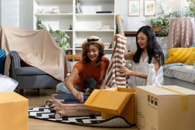 İki güzel kadın, parlak, dekore edilmiş oturma odasında kutuları taşıyan bir bavulu boşaltıp yeni bir ev dekore etmeye hazırlanıyorlar, konuşuyorlar ve birlikte mutlulukla gülümsüyorlar.