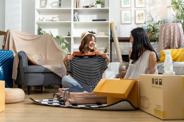 İki güzel kadın, parlak, dekore edilmiş oturma odasında kutuları taşıyan bir bavulu boşaltıp yeni bir ev dekore etmeye hazırlanıyorlar, konuşuyorlar ve birlikte mutlulukla gülümsüyorlar.