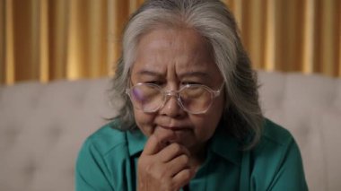 Görüntüler kilitli, gözlüklü Asyalı son sınıf öğrencisinin evinde dizüstü bilgisayar kullanırken düşünceli, düşünceli ifadesini, endişeli ifadesini ve yüzündeki endişeyi veya düşüncelere daldırma görüntüsü.