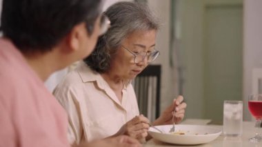 Yakın çekim, seçici odaklanma, gözlüklü iki son sınıf öğrencisi oturmuş lezzetli yemekler yiyor, tartışır ve birlikte gülerler.