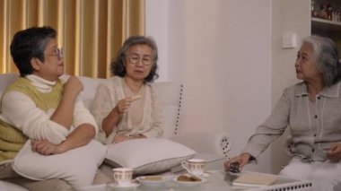 El kamerası görüntüsü, oturma odasındaki kanepede oturan üç Asya 'lı yaşlı kadın uzaktan kumandayı kanal değiştirmek için kullanıyorlar ve mutlu bir şekilde konuşup gülüyorlar.