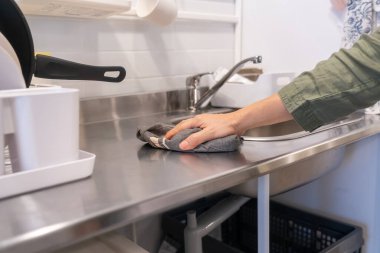 Bulaşık ve çatal bıçaklarla çevrili, paslanmaz çelik mutfak tezgahının eli, gıda hazırlama alanlarında hijyenin önemini gözler önüne seriyor..