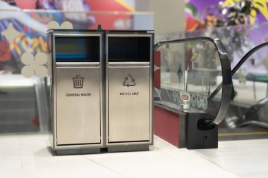 Two waste separation bins placed near escalator in shopping mall,  Bins are designed for general waste and recyclable materials, with clear labels and icons indicating their purpose for environment clipart