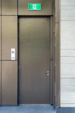 Yeraltı otoparkında işaret olan acil çıkış kapısı. Kolay erişim için metal kapı yatay itme çubuğu. Çevredeki duvarlar betondan yapılmış.