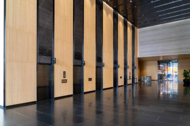 Contemporary elevator lobby featuring three modern elevators with polished metal doors. The lobby is adorned with elegant wooden paneling on the walls minimalistic and professional environments. clipart