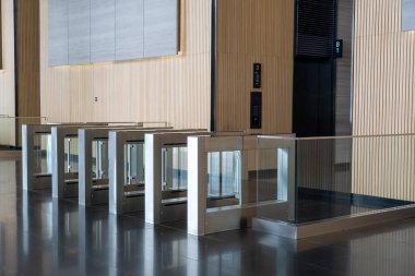 Modern güvenlik turnikeleri şık, çağdaş lobide yer alıyor. Turnikeler cam ve metalden yapılmış, hem estetik hem de güvenliğe odaklı ticari binada güvenli giriş noktası sağlıyor.