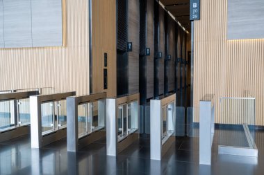 Modern güvenlik turnikeleri şık, çağdaş lobide yer alıyor. Turnikeler cam ve metalden yapılmış, hem estetik hem de güvenliğe odaklı ticari binada güvenli giriş noktası sağlıyor.