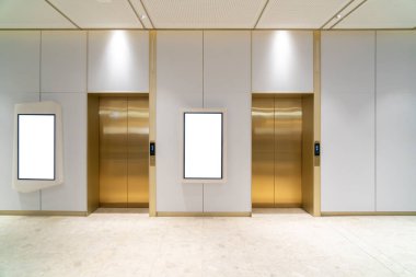 Koridorun lobisinde cilalı metal kapıları olan iki modern asansör lobisi asansörler arasında çerçeve bulunan pano, reklam ya da duyuru için boş alan