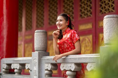 Güzel kırmızı Qipao giymiş gülümseyen kadın portresi geleneksel Çin tapınağında zarafetle duruyor. Geleneksel ay veya Çin Yeni Yıl kutlamaları, kopyalama alanı