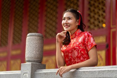 Güzel kırmızı Qipao giymiş gülümseyen kadın portresi geleneksel Çin tapınağında zarafetle duruyor. Geleneksel ay veya Çin Yeni Yıl kutlamaları, kopyalama alanı