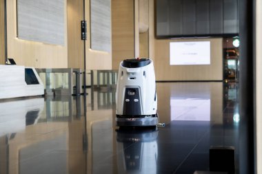 Otomatik Temizlik Robotu modern binanın lobisinde hareket halinde. Koridorda otomatik olarak çalışacak programa göre yerleri süpürüp yerleri süpürüyor.