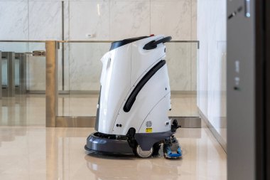 Yan görünüm, otonom zemin temizleme robotu modern binanın lobisinde hareket halinde, koridorlarda otomatik olarak çalışacak programa göre yerleri süpürme ve süpürme
