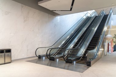 Çağdaş yürüyen mermer duvarları ve minimalist tasarımı olan temiz, iyi ışıklandırılmış bir alışveriş merkezi içine kurulmuş, duvarın yanına yerleştirilmiş iki çöp, resimde insan yok.