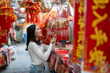 Geleneksel Çin Yeni Yılı Alışveriş Süslemeleri için keşif yapan genç ve güzel bir kadının portresi piyasada geleneksel ritüel eşyalara göz atıp onları satın almaktan mutluluk duyuyordu.