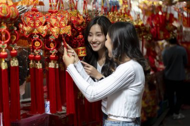 Seçici odaklanma, genç kadın ve arkadaş açık hava pazarından güzel geleneksel ürünleri inceleyip satın alıyor, kültürel alışveriş deneyiminden hoşlanıyor, konuşuyor ve birlikte mutlu bir şekilde gülümsüyor.