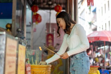 Genç ve güzel bir kadın, tütsü demetini dikkatlice renkli dekorasyonları ve geleneksel unsurları olan büyük, süslü bir tütsü yakıcısına yerleştiriyor..