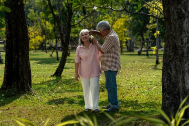 Asyalı yaşlı bir çiftin halka açık bir parkta kaliteli zaman geçirmesi ne hoş. Karının elini tutan koca ve sıcak güneş ışığında yürürken gülümseyen, sevgi ve aile anını paylaşan adam.