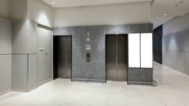 Asansör kapıları ve boş reklam ekranı olan modern ofis binası, şık ışıklandırmalı temiz ve minimal ticari alan, ticari markalaşma ve kurumsal tabelalar için mükemmel