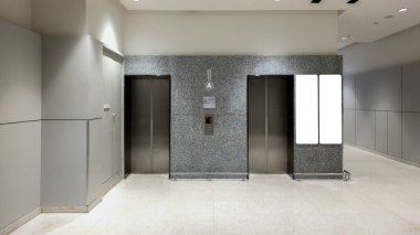 Asansör kapıları ve boş reklam ekranı olan modern ofis binası, şık ışıklandırmalı temiz ve minimal ticari alan, ticari markalaşma ve kurumsal tabelalar için mükemmel