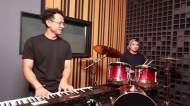 Asyalı klavyeci ve davulcu ses tedavi odasındaki gündelik müzik reçeli seansında gülüşlerini paylaşıyorlar.
