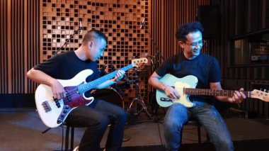 İki erkek müzisyen akustik kayıt stüdyosunda birlikte müzik çalıyorlar, biri bas gitarda, diğeri de elektro gitarda, profesyonel ortamlarda rahat ve yaratıcı ruh halinde.