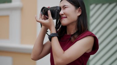Genç Asyalı kadın kameradan dışarı odaklanmış bir ifadeyle fotoğrafçılığa zarif ve net bir şekilde yaratıcı ve kendinden emin bir an yakalıyor..