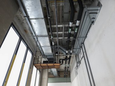 Mekanik borular, hava kanalları, kablo çekmeceleri ve kanal hatları olan tamamlanmamış binanın içindeki tavan, HVAC kurulumu, mühendislik düzeni veya altyapı kurulum süreci için ideal.