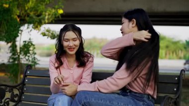 İki genç Asyalı kadın parkta bankta oturuyor, biri diğerinin duygusal görünmesine yardım ediyor. Tartışma sırasında el ele tutuşuyorlar. Bir destek ve dostluk anı..