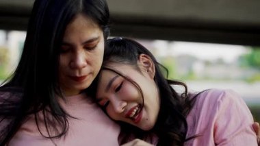 İki genç Asyalı kadın parkta bankta oturuyor, biri diğerinin duygusal görünmesine yardım ediyor. Tartışma sırasında el ele tutuşuyorlar. Bir destek ve dostluk anı..