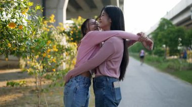 İki genç Asyalı kadın parkta bankta oturuyor, biri diğerinin duygusal görünmesine yardım ediyor. Tartışma sırasında el ele tutuşuyorlar. Bir destek ve dostluk anı..