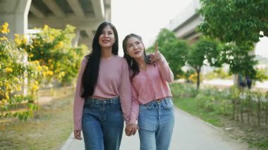 İki genç Asyalı kadın parkta bankta oturuyor, biri diğerinin duygusal görünmesine yardım ediyor. Tartışma sırasında el ele tutuşuyorlar. Bir destek ve dostluk anı..