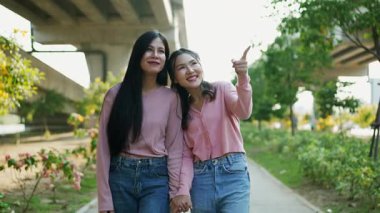 İki genç Asyalı kadın parkta bankta oturuyor, biri diğerinin duygusal görünmesine yardım ediyor. Tartışma sırasında el ele tutuşuyorlar. Bir destek ve dostluk anı..