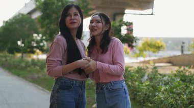 İki genç Asyalı kadın parkta bankta oturuyor, biri diğerinin duygusal görünmesine yardım ediyor. Tartışma sırasında el ele tutuşuyorlar. Bir destek ve dostluk anı..