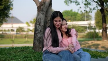 İki genç Asyalı kadın parkta bankta oturuyor, biri diğerinin duygusal görünmesine yardım ediyor. Tartışma sırasında el ele tutuşuyorlar. Bir destek ve dostluk anı..