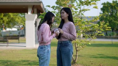 İki genç Asyalı kadın parkta bankta oturuyor, biri diğerinin duygusal görünmesine yardım ediyor. Tartışma sırasında el ele tutuşuyorlar. Bir destek ve dostluk anı..