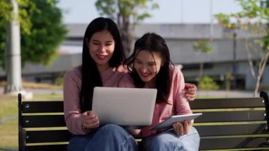 İki genç Asyalı kadın parkta bankta oturuyor, biri diğerinin duygusal görünmesine yardım ediyor. Tartışma sırasında el ele tutuşuyorlar. Bir destek ve dostluk anı..