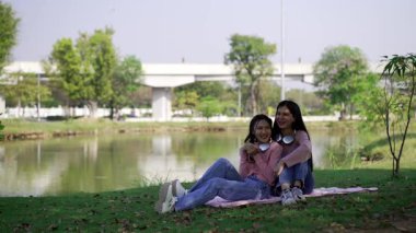 İki genç Asyalı kadın parkta bankta oturuyor, biri diğerinin duygusal görünmesine yardım ediyor. Tartışma sırasında el ele tutuşuyorlar. Bir destek ve dostluk anı..