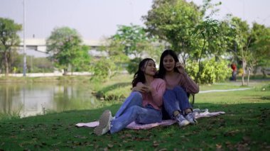 İki genç Asyalı kadın parkta bankta oturuyor, biri diğerinin duygusal görünmesine yardım ediyor. Tartışma sırasında el ele tutuşuyorlar. Bir destek ve dostluk anı..