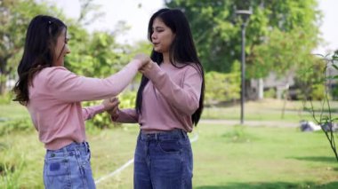 İki genç Asyalı kadın parkta bankta oturuyor, biri diğerinin duygusal görünmesine yardım ediyor. Tartışma sırasında el ele tutuşuyorlar. Bir destek ve dostluk anı..