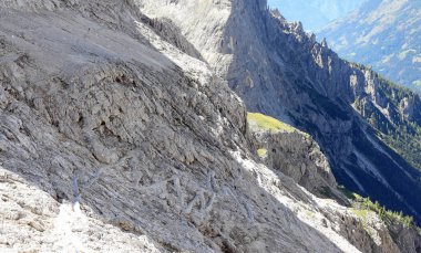 Sırt çantalı genç bir kadın dağ yolunda yürürken omuzlarında.