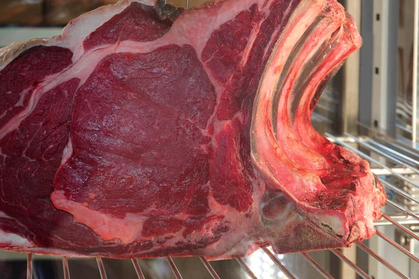 large piece of raw rib eye steak in the butcher's refrigerator