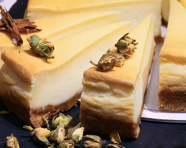 チーズとレモンで作られたケーキのスライスと香りの良い香りのためのいくつかの乾燥バラの芽 — ストック写真