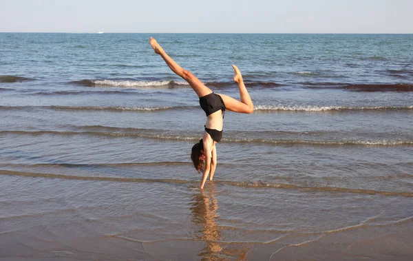 苗条身材的女孩背靠背地做瑜伽冥想练习 用手在海边做Om符号 — 图库照片