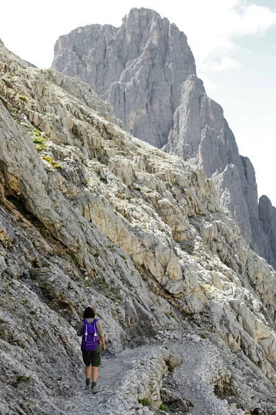 年轻女子背着背包走在阿尔卑斯山的石子路上 — 图库照片