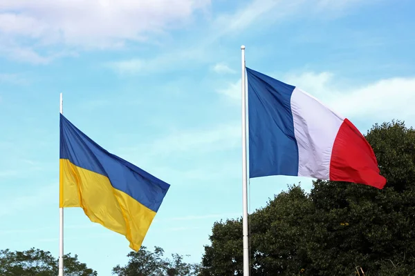 stock image yellow and blue flags of ukraine and the french flag waving together