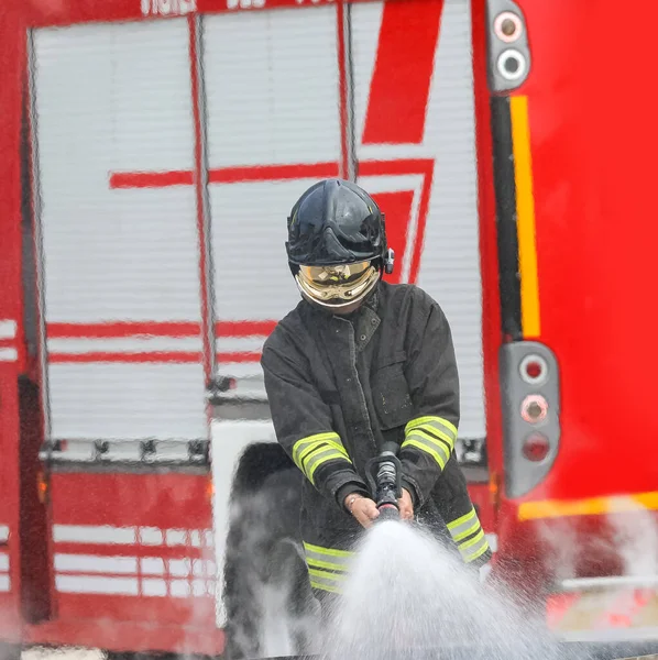 Feuerwehrmann Mit Helm Und Schutzvisier Beim Löschen Eines Feuers Mit — Stockfoto
