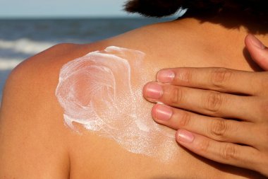 Sevecen bir şekilde kızın sırtına güneş kremi sürüyor.