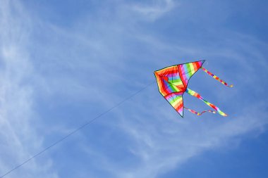 Gökkuşağı renginde büyük bir uçurtma Mavi gökyüzünde uçuyor