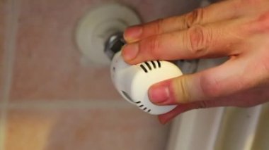 hand closing the radiator valve to save gas in winter